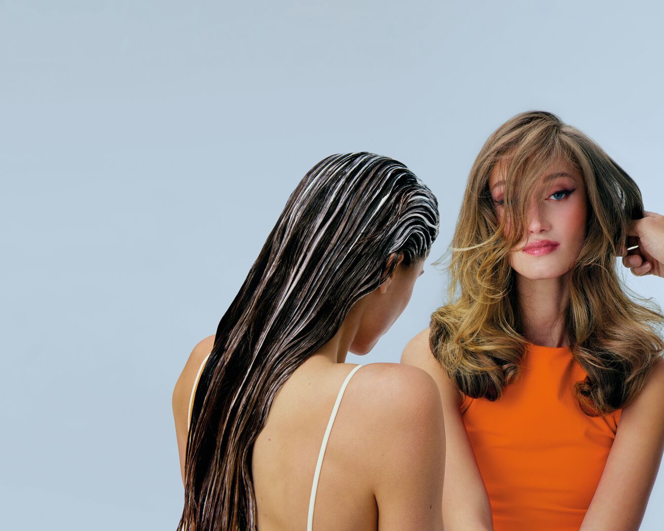 Deux femmes présentent des coiffures différentes : l'une a les cheveux bruns avec un traitement, l'autre a les cheveux blonds coiffés par une main.
