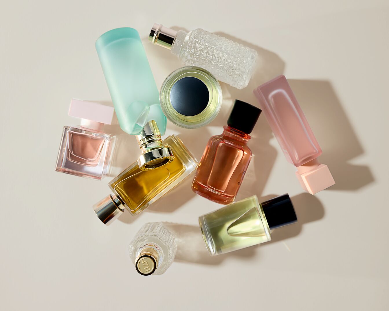 Een verzameling diverse parfumflesjes in verschillende kleuren en vormen, waaronder helder glas, pastel tinten en gouden accenten.