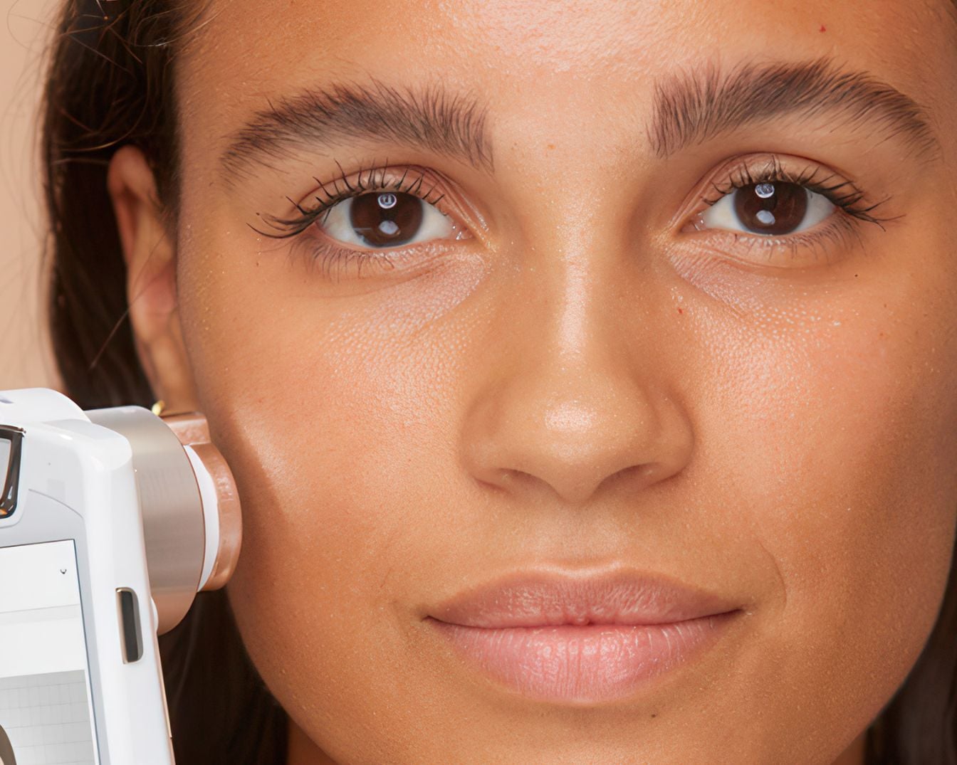 Zbliżenie na twarz kobiety, na której skóra jest badana za pomocą urządzenia diagnostycznego, co pozwala na dokładną analizę stanu cery.