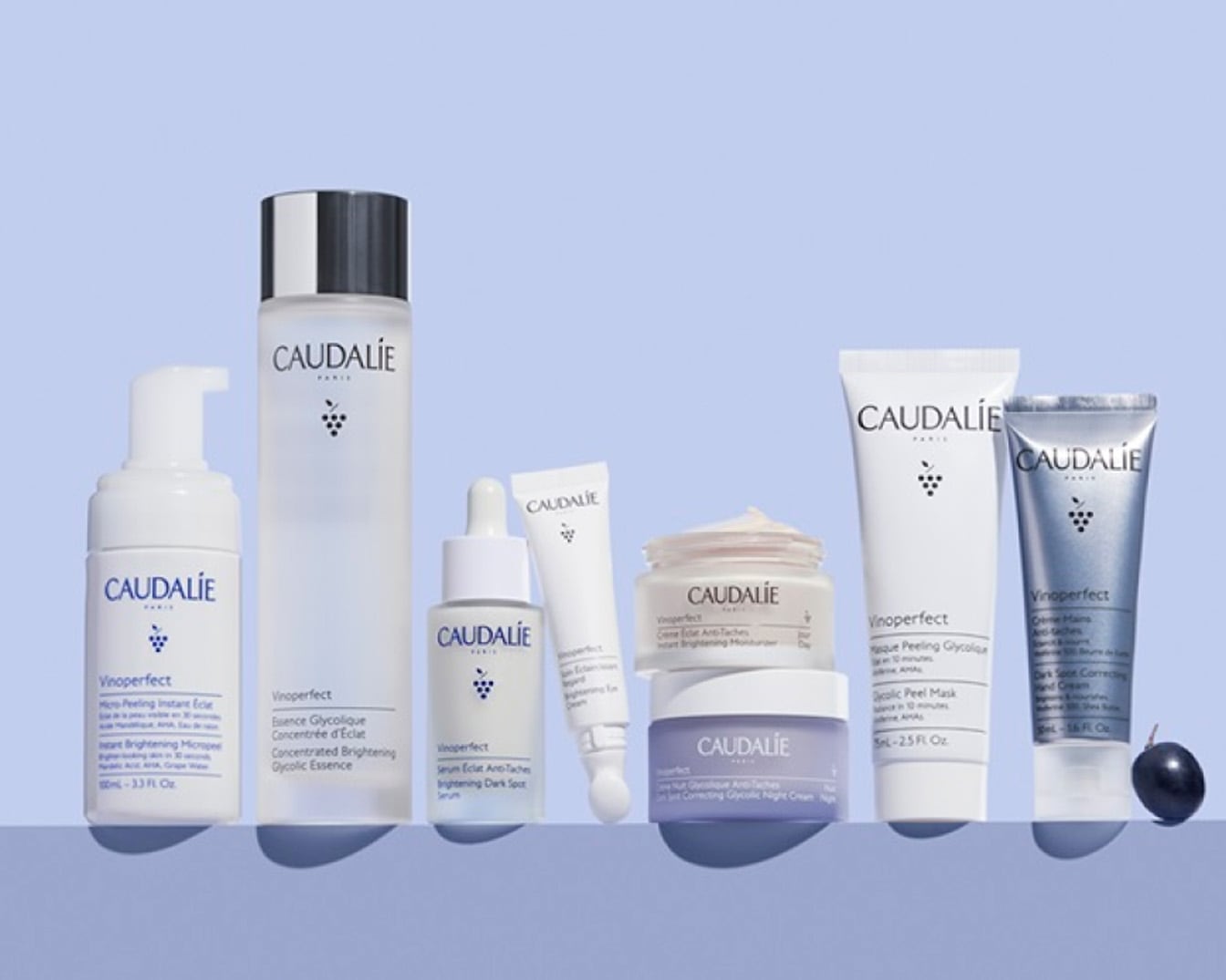 Kolekcja kosmetyków Caudalie Vinoperfect w białych opakowaniach, zawierająca esencję glikolową, serum rozjaśniające i kremy, które pomagają w walce z przebarwieniami i dodają blasku skórze.