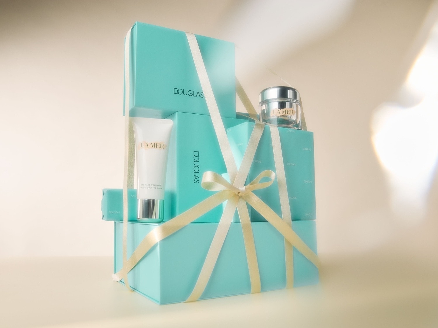 La Mer Geschenkset, präsentiert in einer eleganten, gestapelten Verpackung in Türkis, verziert mit einer zarten Schleife in Creme.