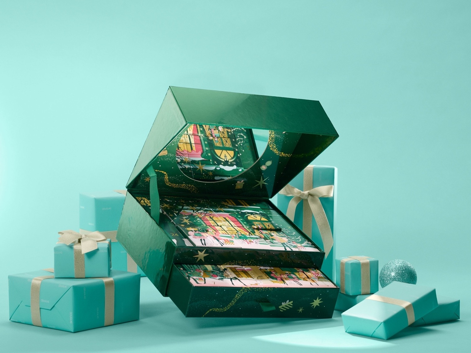 Zelený adventný kalendár s otvoreným vekom odhaľuje vianočnú scénu, obklopený tyrkysovými darčekmi so zlatými stuhami.