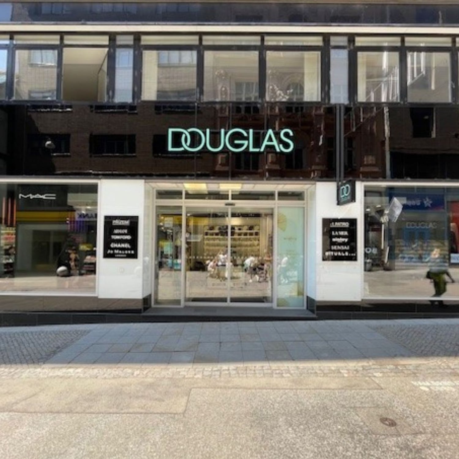 Pohled zvenčí na prodejnu Douglas s automatickými dveřmi a nápisem Douglas nad vchodem.
