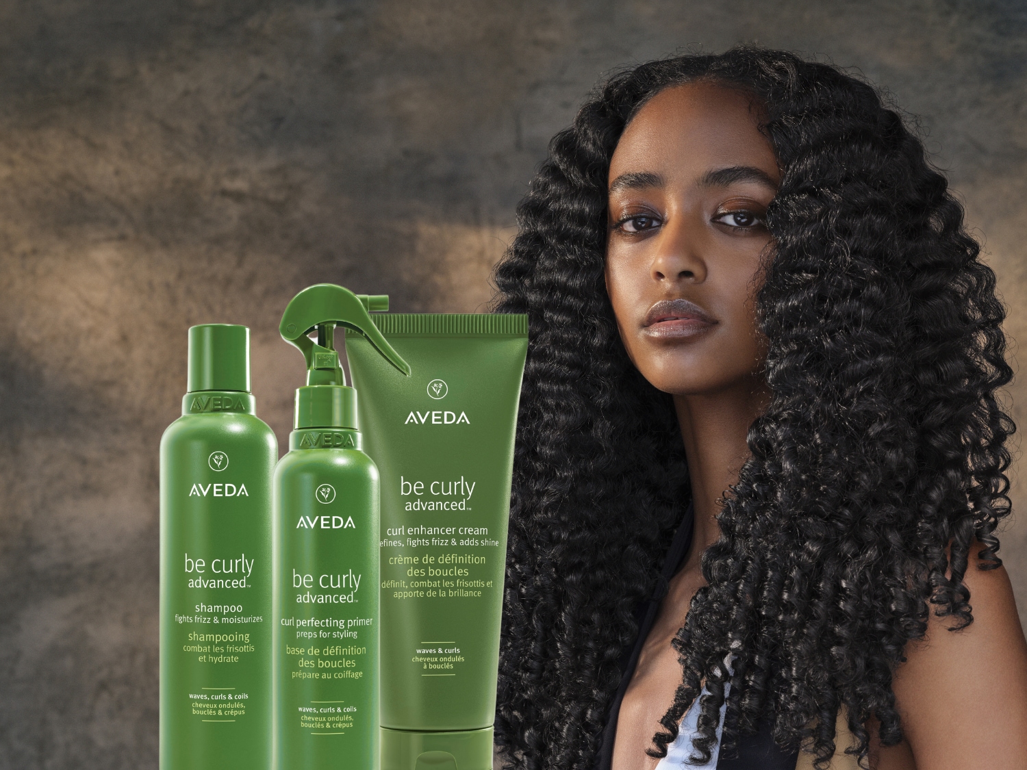 Aveda's Be Curly Advanced haarverzorgingslijn, met shampoo, primer en krulversterkende crème in groene verpakkingen, belooft gedefinieerde, pluisvrije krullen.