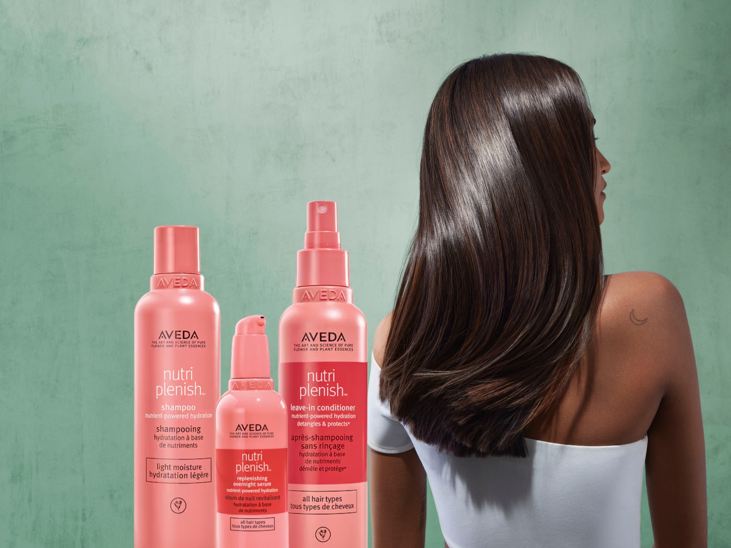 Aveda Nutriplenish haarverzorgingslijn in roze verpakkingen, inclusief shampoo, leave-in conditioner en overnight serum, voor alle haartypes.