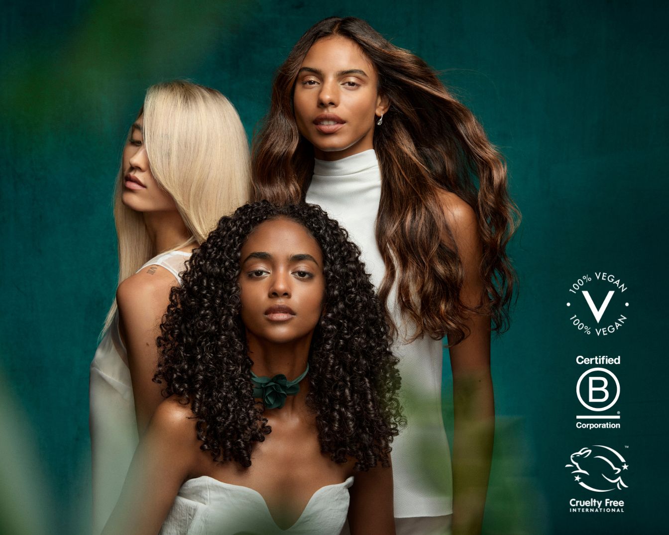 Drie modellen met blond, bruin en krullend haar staan tegen een groene achtergrond, met logo's die 100% veganistisch en dierproefvrij aangeven.