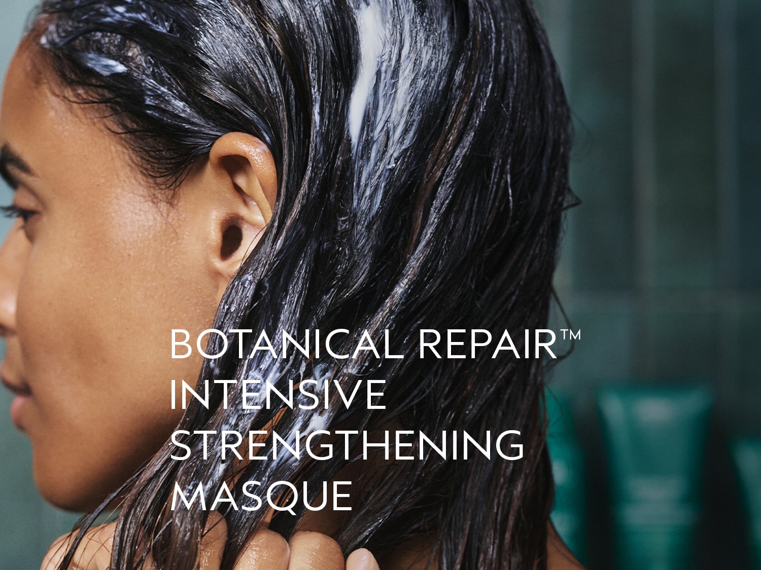 Een vrouw met donker haar heeft een witte Botanical Repair Intensive Strengthening Masque in haar haar.