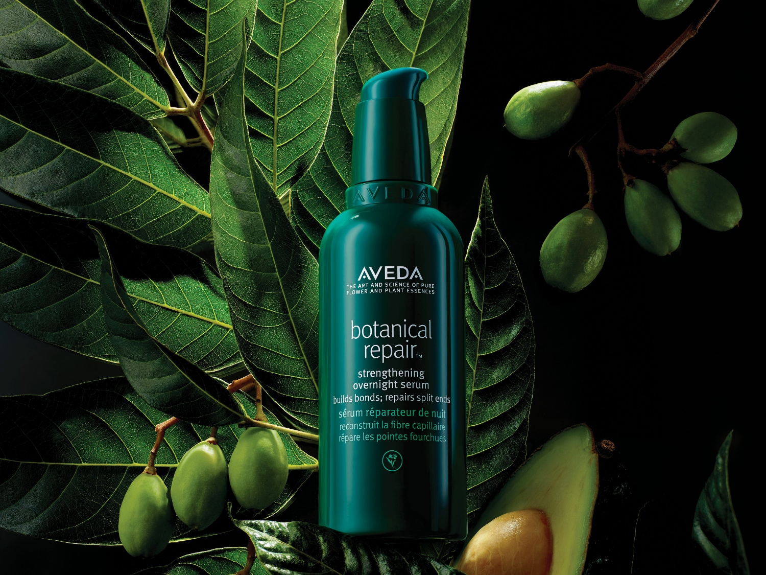 Groene Aveda Botanical Repair nachtserumfles met pompje, omringd door bladeren en groene vruchten, belicht de natuurlijke ingrediënten voor het herstellen van gespleten haarpunten.