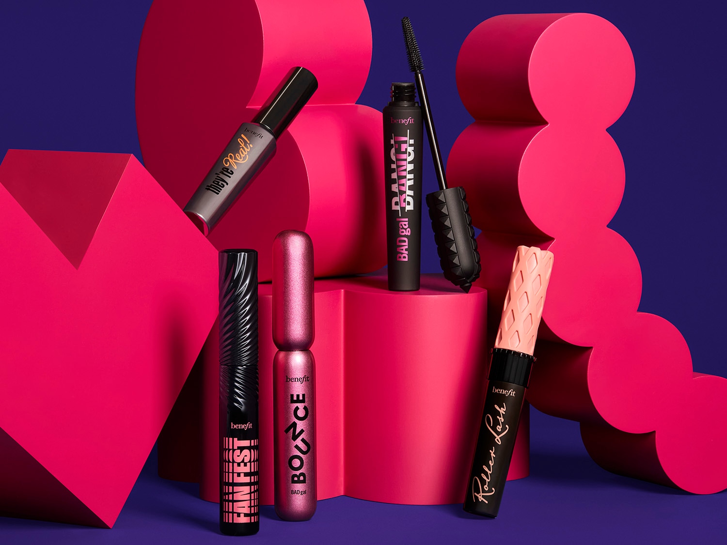 Découvrez une gamme de mascaras Benefit : They're Real!, Bad Gal Bang!, Fan Fest, Roller Lash et Boi-ing Bounce, présentés sur un fond violet et des formes géométriques roses.