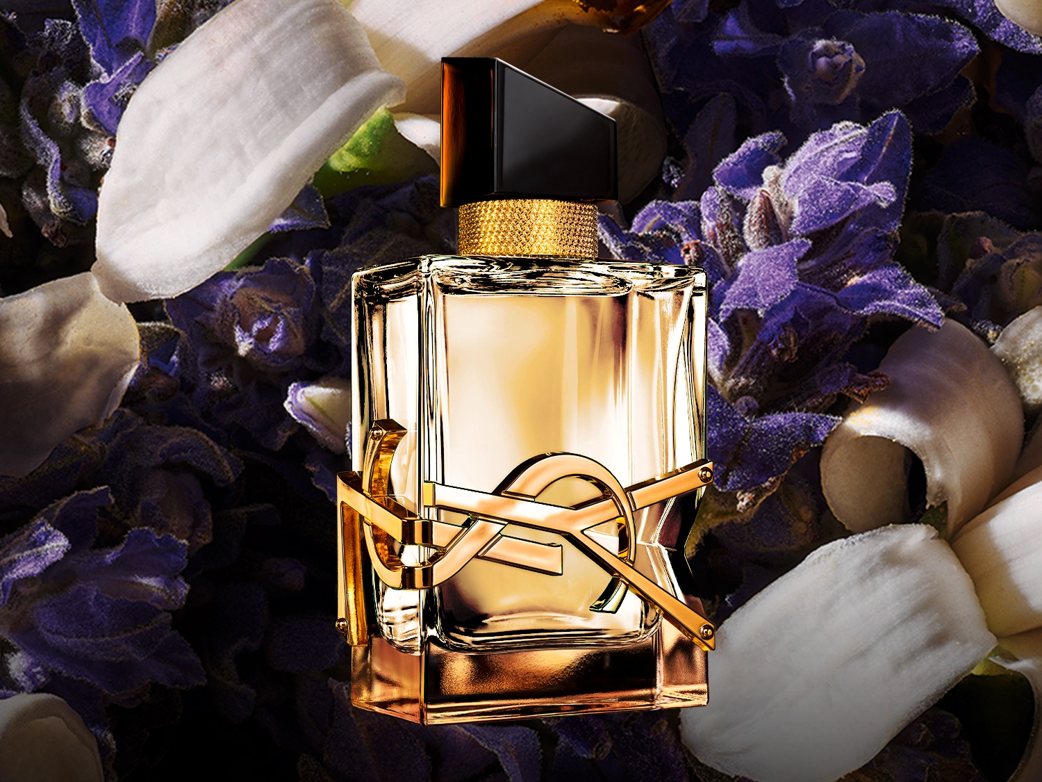 Le parfum YSL est présenté dans un flacon en verre transparent avec un logo doré, sur un fond de fleurs violettes et de pétales blancs.