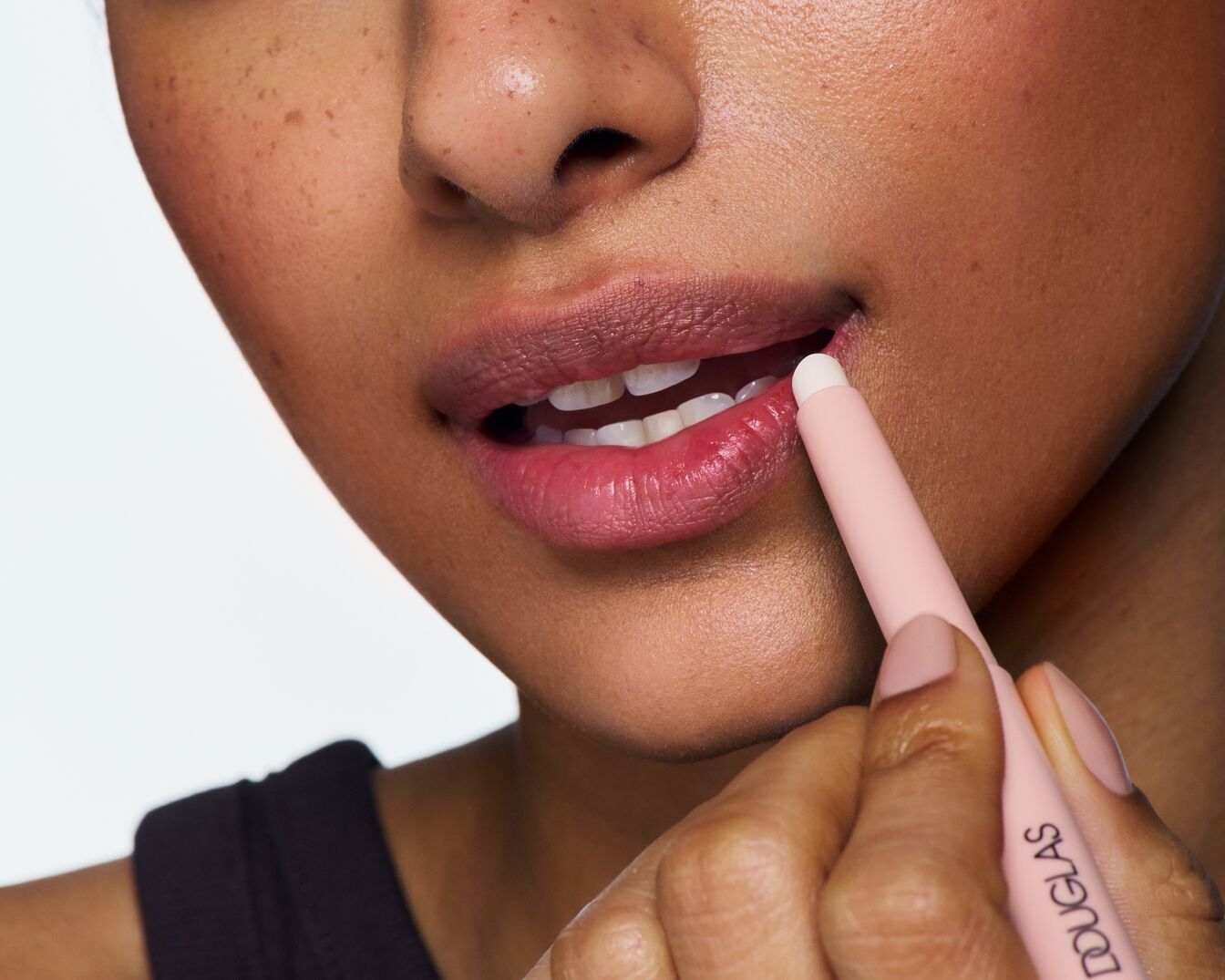 Detail obličeje s rtěnkou Douglas v růžovém obalu, která se nanáší na rty pro zvýraznění jejich přirozené barvy.