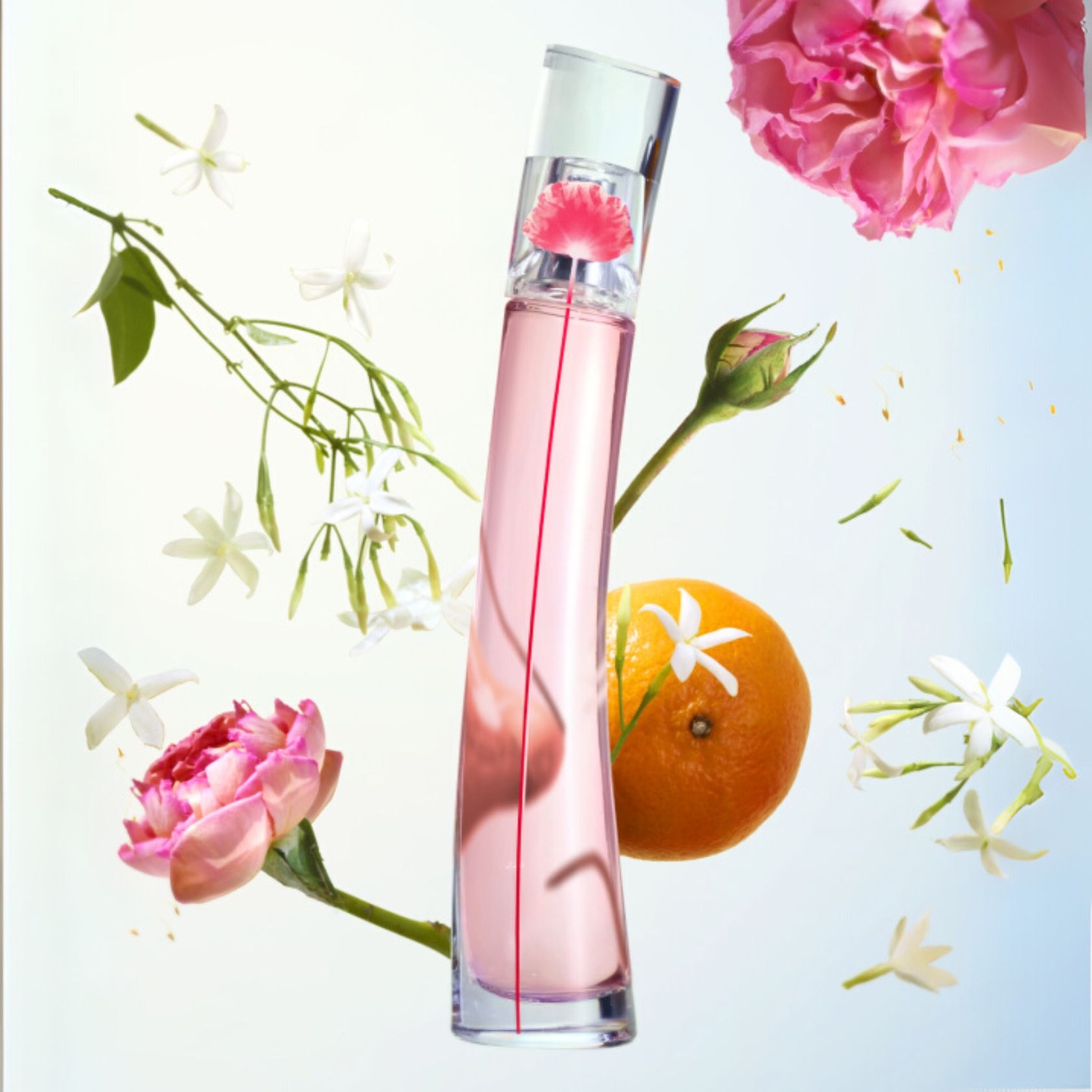 Ein schlanker, rosafarbener Parfümflakon steht inmitten von Rosen, Jasminblüten und einer Orange, die ein Gefühl von Frische und floraler Eleganz vermitteln.