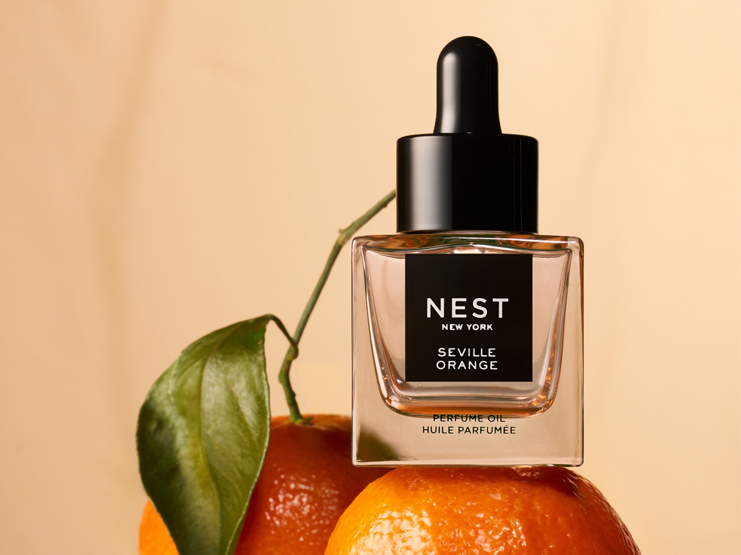 A Nest New York Seville Orange parfümolaj egy narancson ül, átlátszó üvegben, fekete kupakkal és címkével.