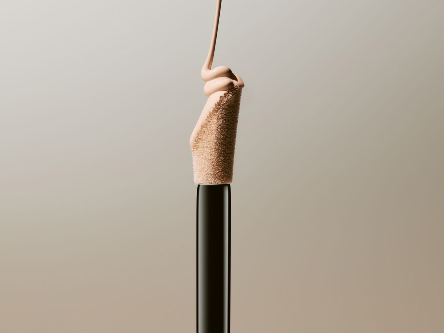 Applicateur de correcteur avec une goutte de produit beige clair, offrant une couvrance impeccable pour un teint uniforme.