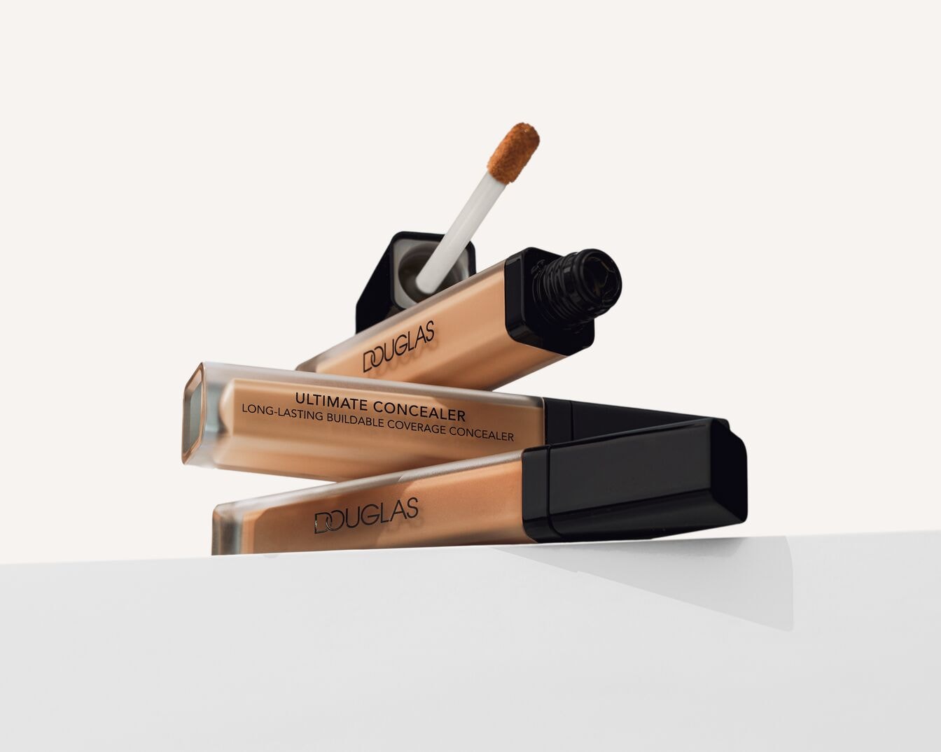 Stapel Douglas Ultimate Concealers in transparante verpakking met zwarte dop, de applicator steekt uit een van de geopende tubes.