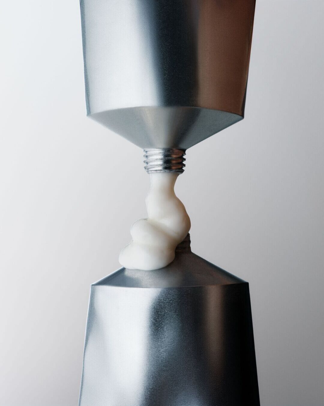 Sidabrinis tūbelė su baltu kremu, išspaustu iš jos, rodo produkto tekstūrą ir naudojimą.