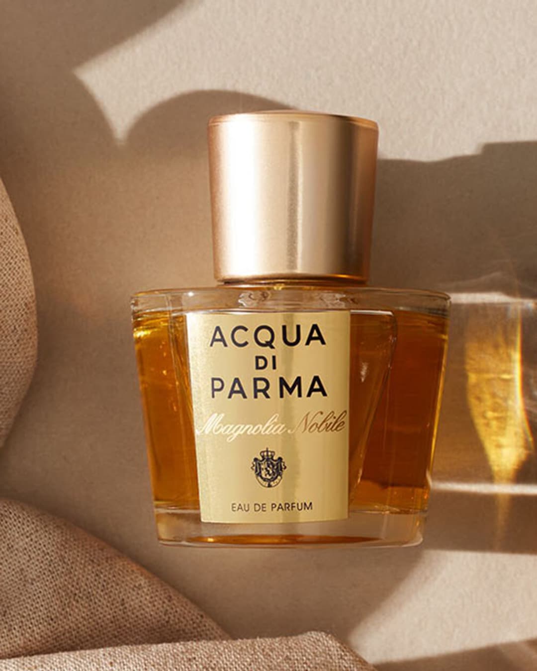 Voici le parfum Acqua di Parma Magnolia Nobile, présenté dans un flacon transparent avec un bouchon doré, évoquant l'élégance italienne.
