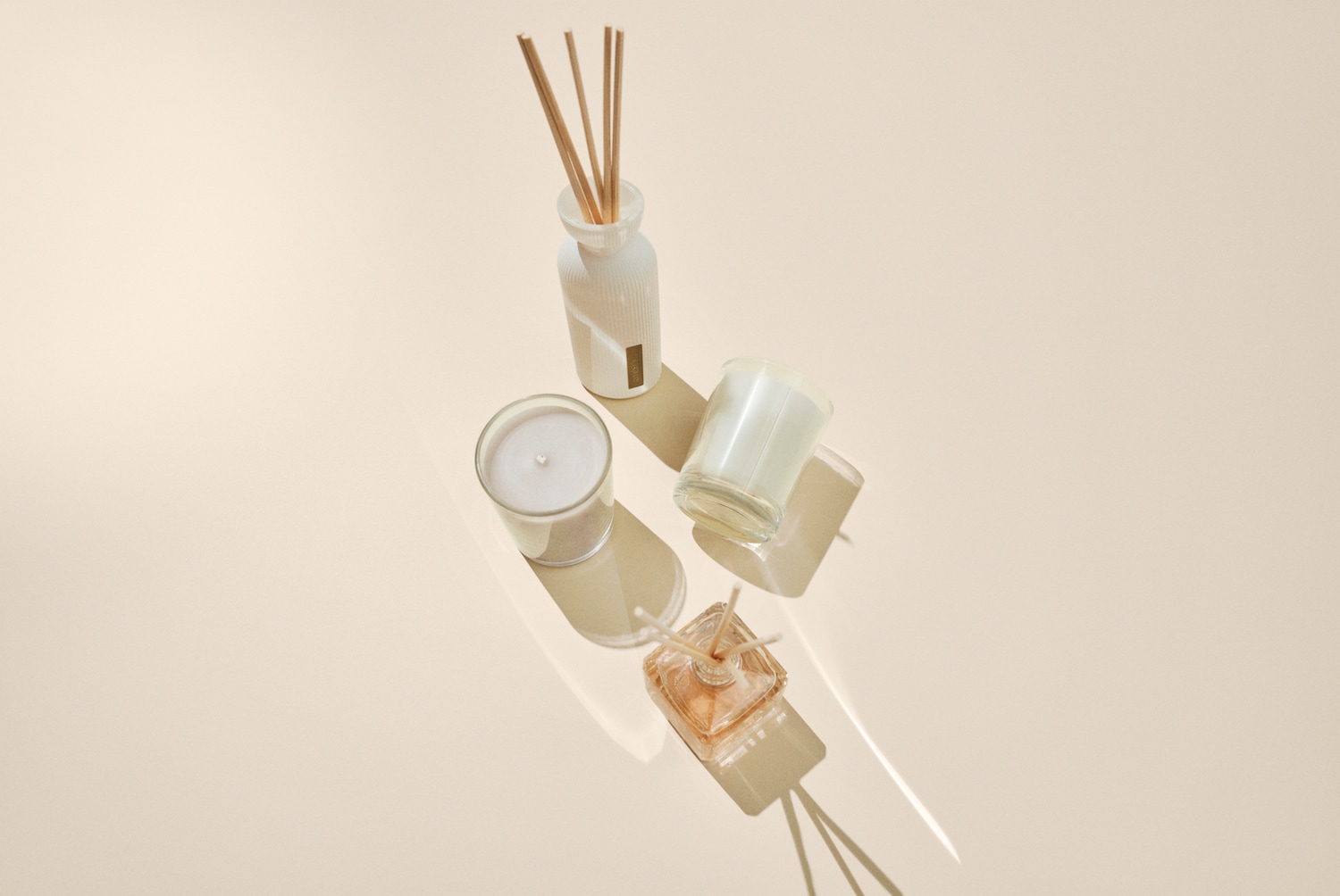 Aromaterapinis rinkinys su žvakėmis stikliniuose indeliuose ir kvapų difuzorius su lazdelėmis, skirtas jaukiai atmosferai sukurti.