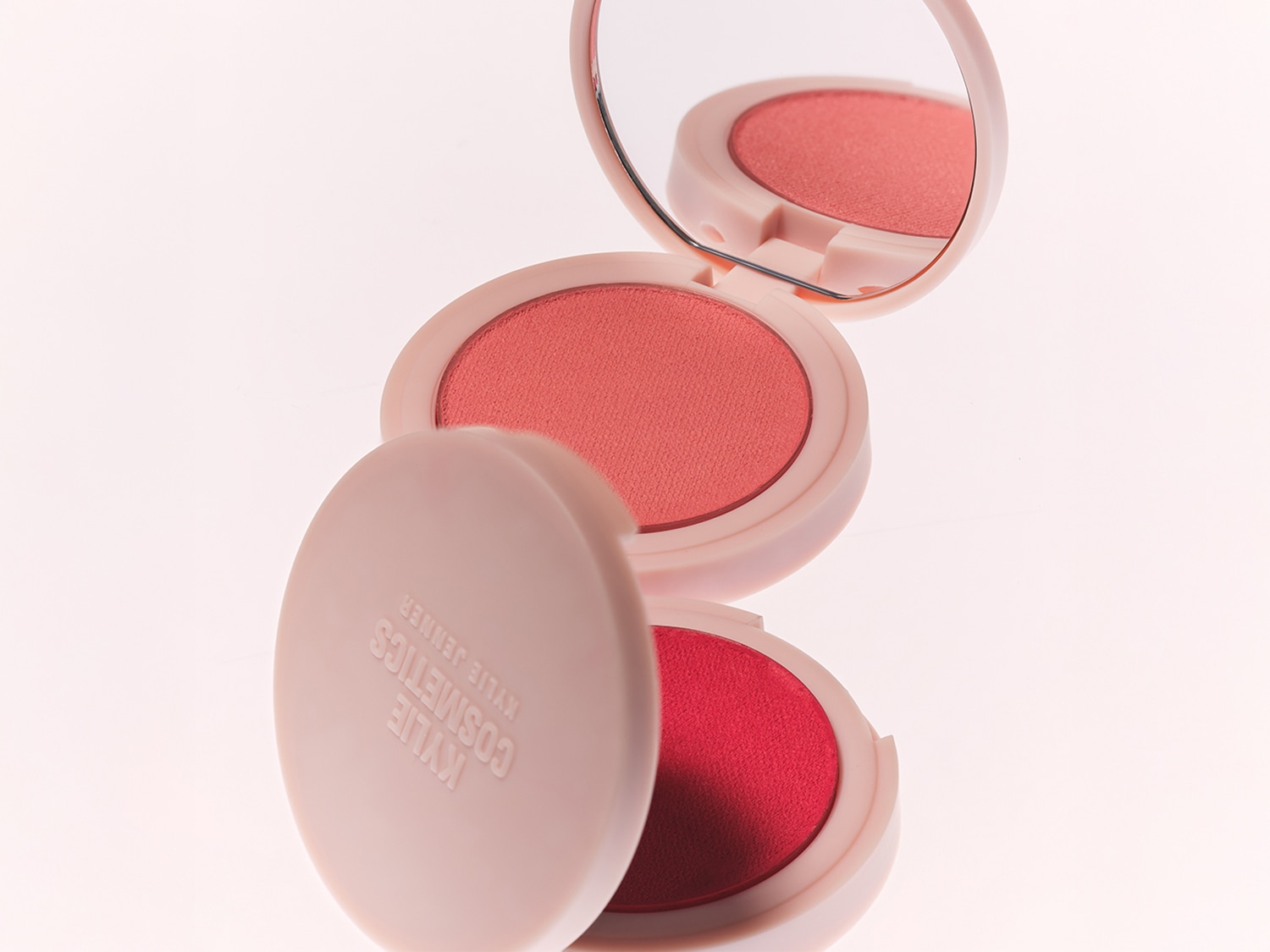 Primo piano di una donna con occhi azzurri mentre applica fondotinta beige con un pennello per un incarnato impeccabile.