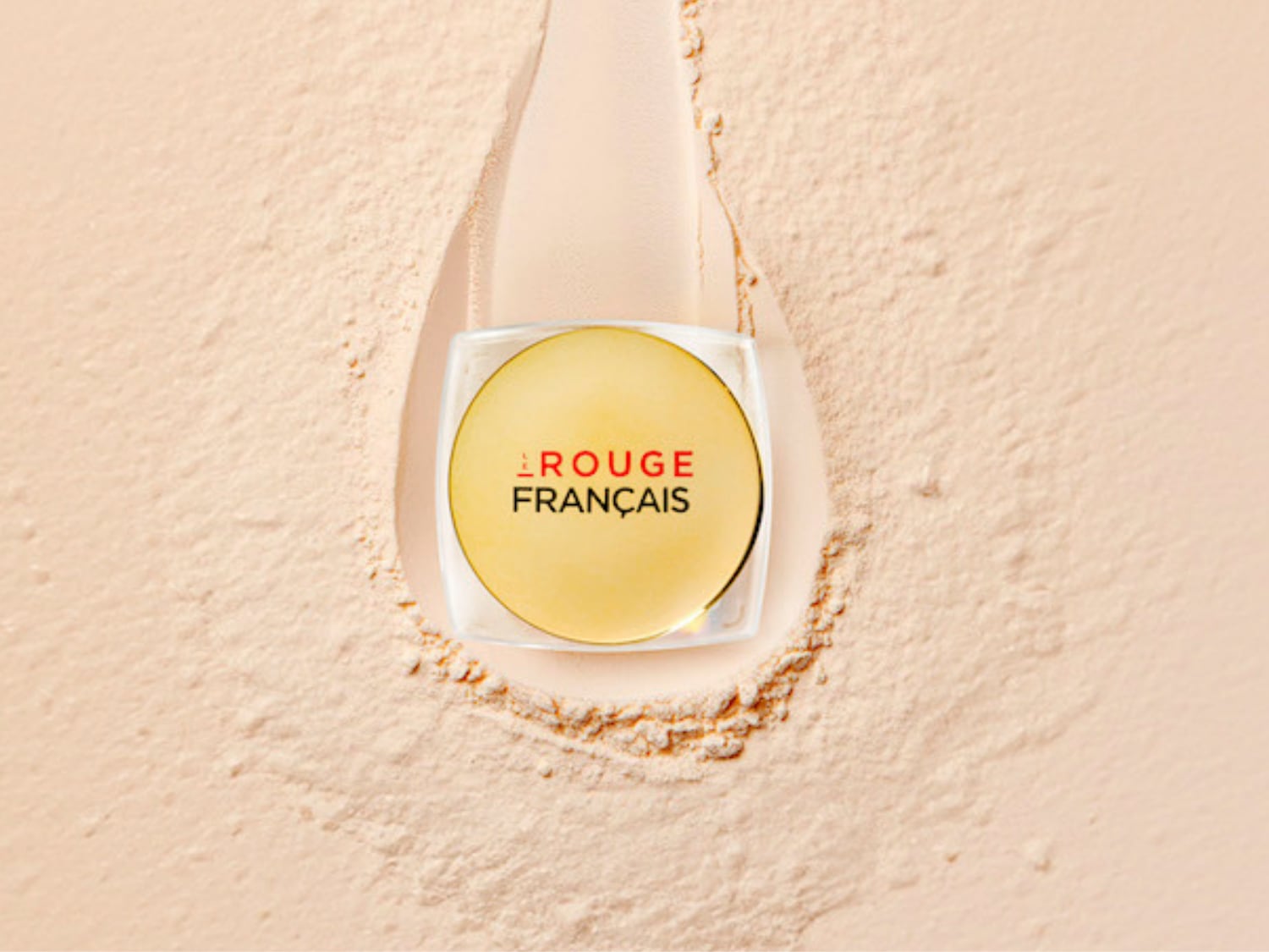 Découvrez la poudre libre Rouge Français, présentée dans un élégant pot doré sur un fond poudré abricot, pour un teint parfait et lumineux.
