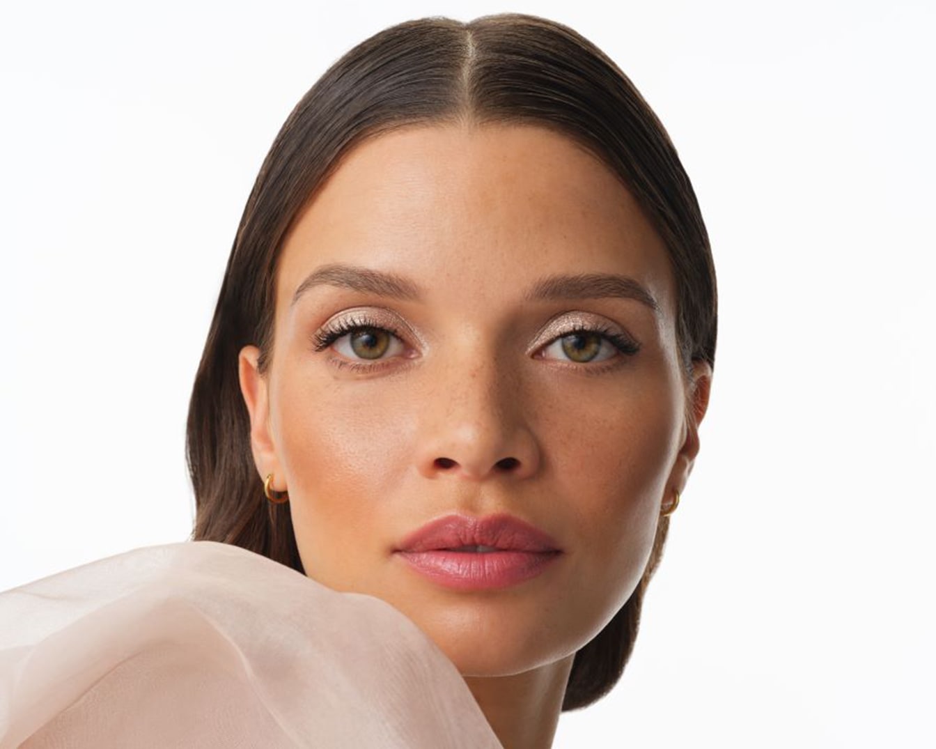 Primo piano di una modella con ombretto scintillante color champagne, labbra rosa e incarnato luminoso, che mette in risalto un look fresco e sofisticato.