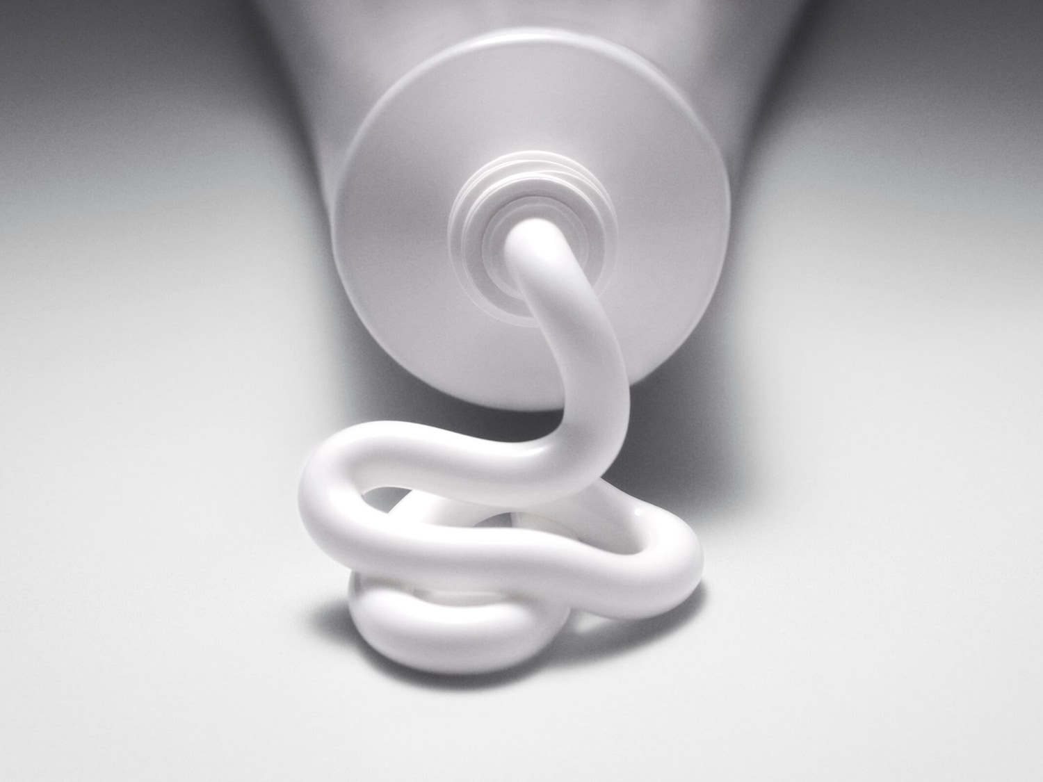 Nahaufnahme einer Tube mit weißer Creme, die in einer gewundenen Form herausgedrückt wird, ideal für Hautpflege oder medizinische Produkte.