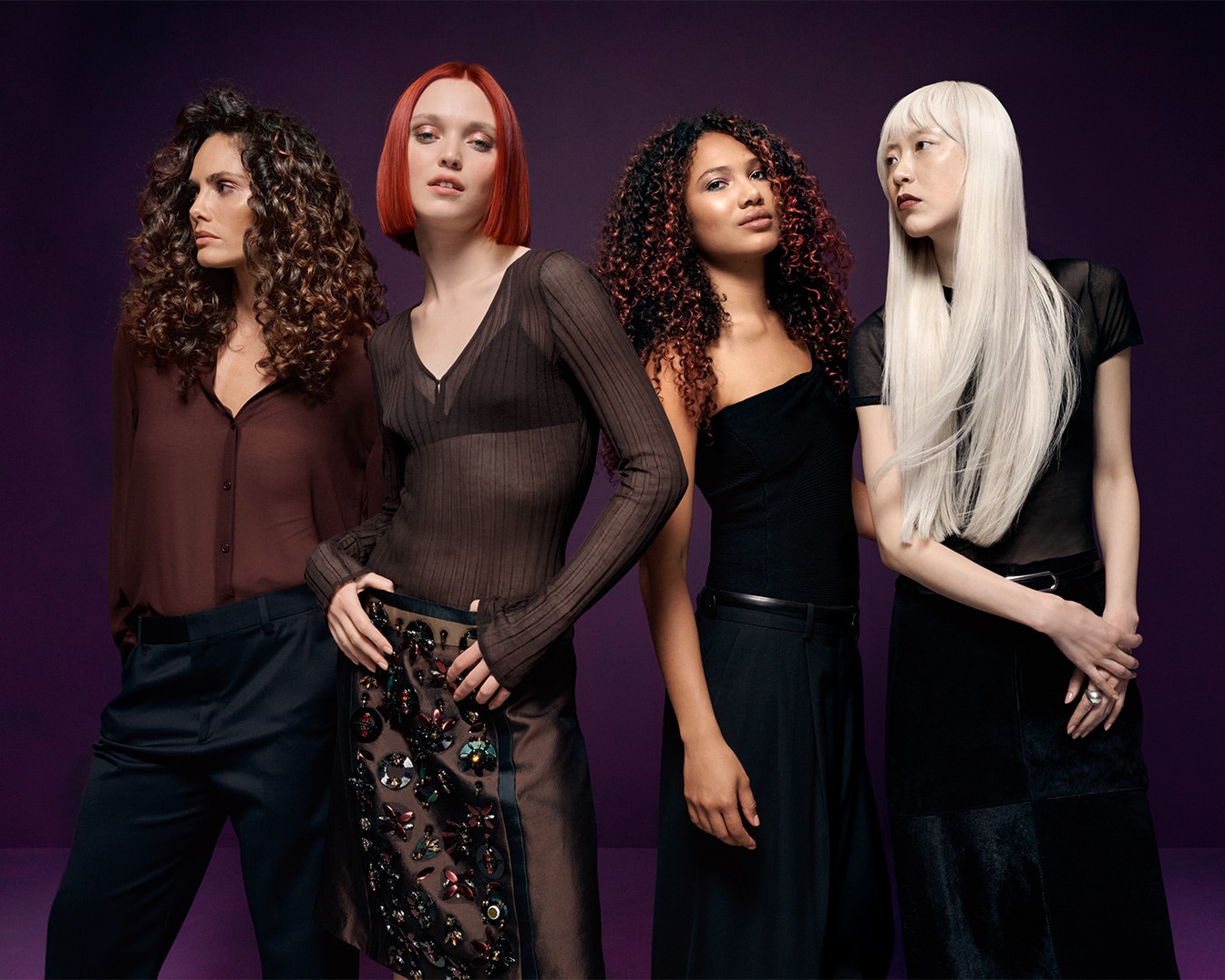 Vier Frauen mit unterschiedlichen Haarfarben und Frisuren stehen vor einem violetten Hintergrund und präsentieren verschiedene Looks.