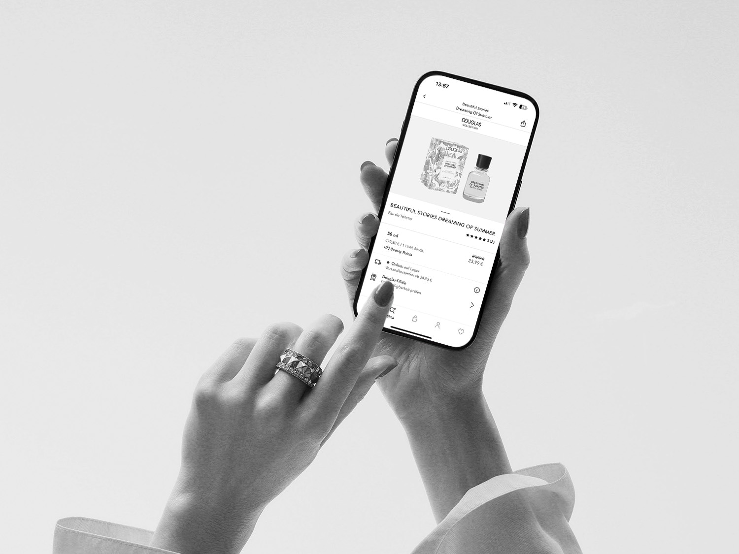 Eine Hand hält ein Smartphone, auf dem die Douglas-App mit dem "Beautiful Stories Dreaming of Summer" Eau de Toilette angezeigt wird, Preis: 23,99 €.