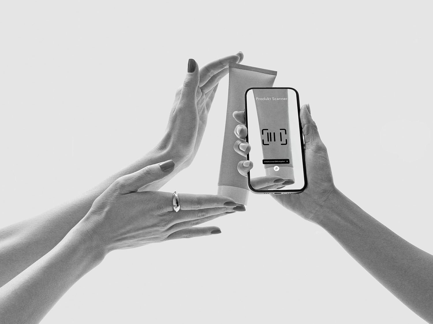 Eine Hand hält ein Smartphone mit der Aufschrift Produkt Scanner, während eine andere Hand eine Tube mit einem Produkt hält, um es zu scannen.