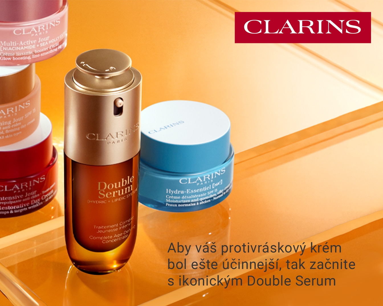 Clarins Double Serum v hnedej fľaštičke so zlatým vrchnákom, vedľa hydratačného krému v modrom obale a ďalších produktov, ktoré sľubujú ešte účinnejší boj proti vráskam.