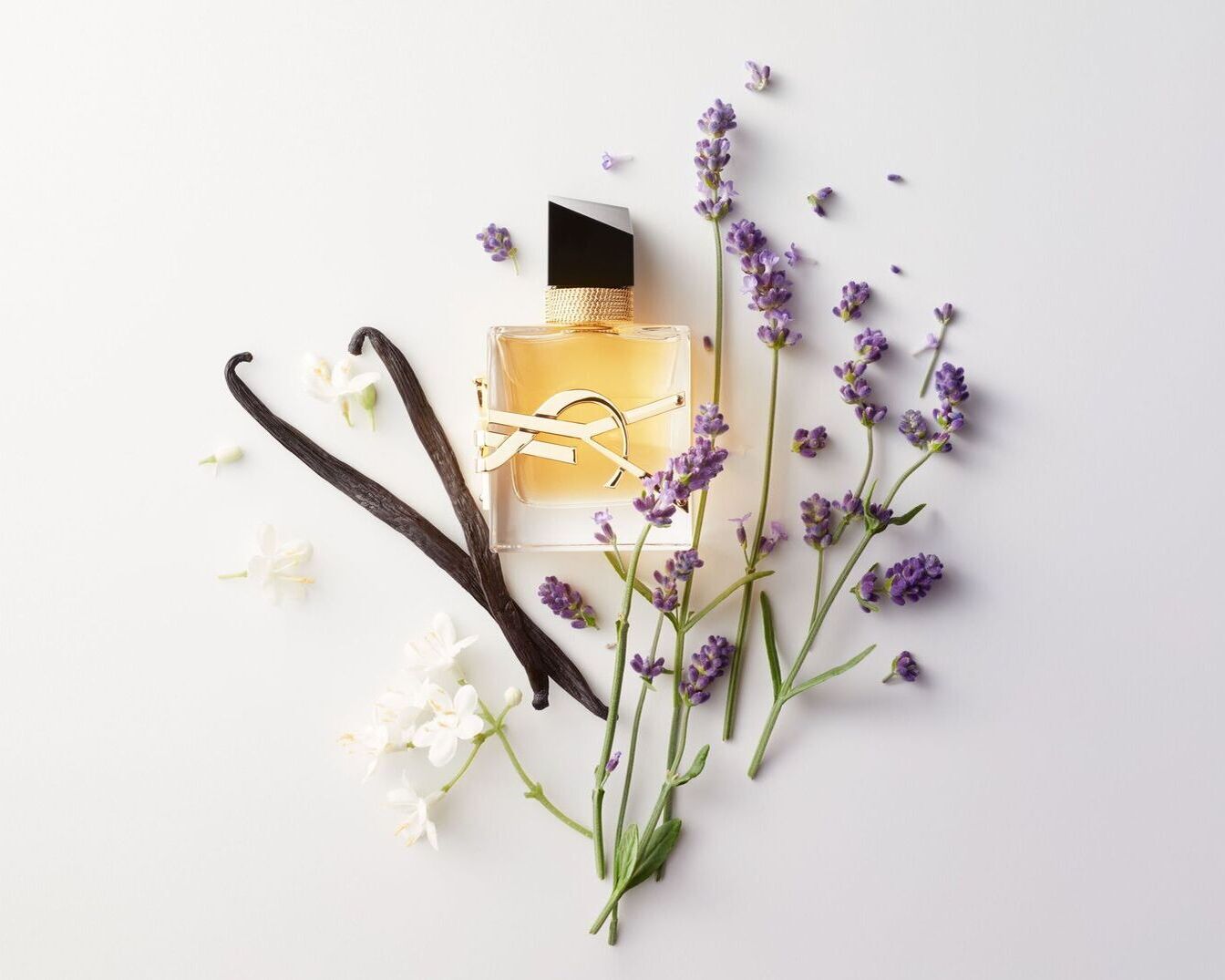 Auksinės spalvos YSL Libre aromatas stikliniame buteliuke su juodu dangteliu, apsuptas levandų žiedų, vanilės ankščių ir baltų žiedų, sukuria prabangos ir gamtos harmoniją.