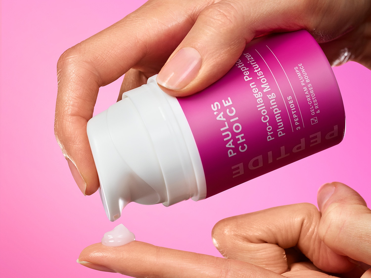 Nahaufnahme einer Hand, die eine kleine Menge Paula's Choice Pro-Collagen Peptide Plumping Moisturizer aus einer weißen Flasche mit pinkfarbenem Etikett auf den Finger gibt.