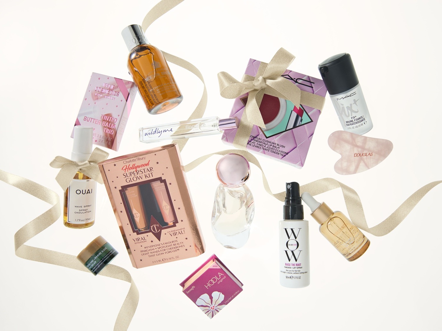 Kosmetické produkty různých značek, včetně Kylie Cosmetics, Charlotte Tilbury a MAC, jsou elegantně uspořádány se zlatou stuhou.