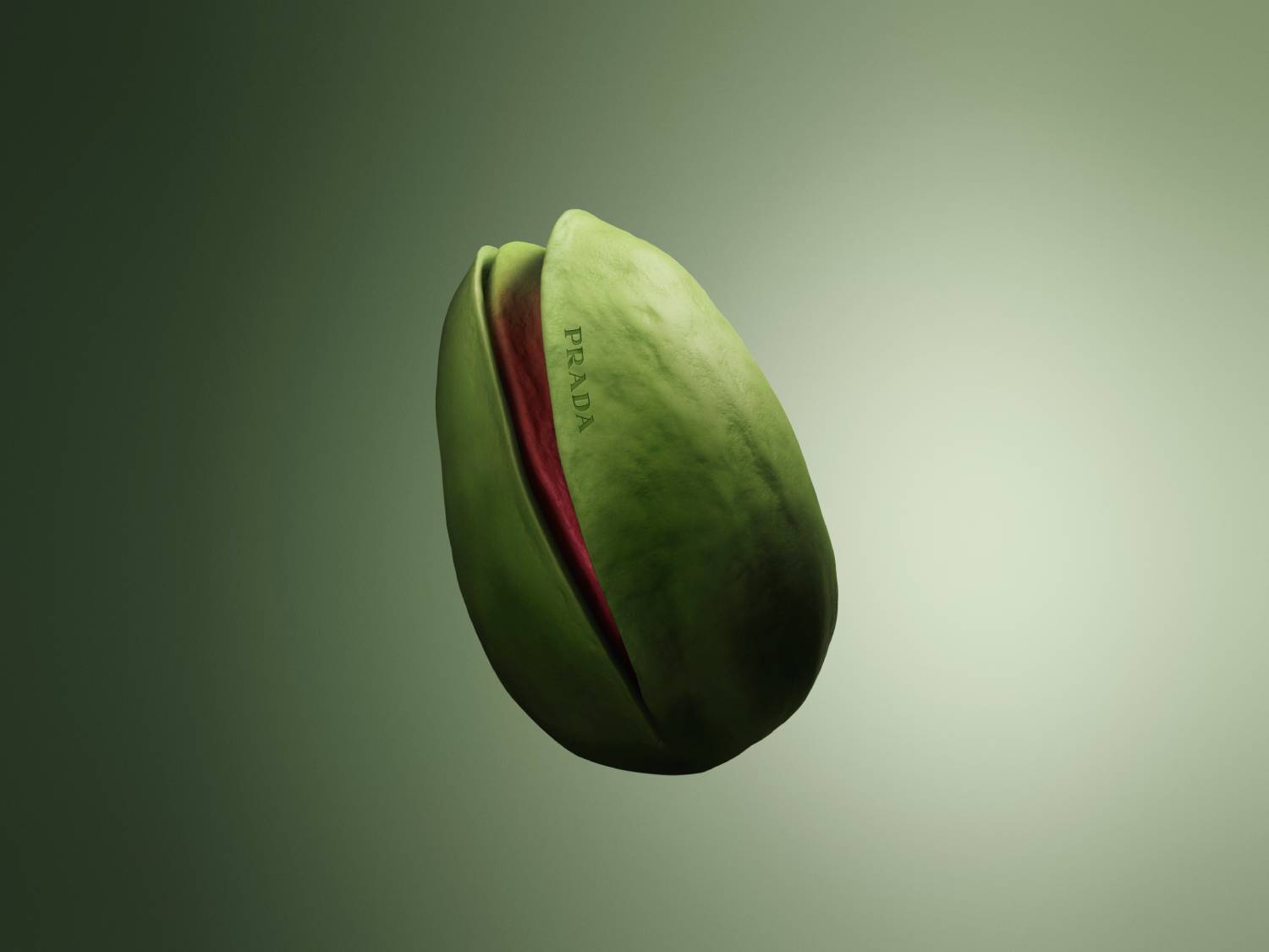 Detailný záber na zelenú pistáciu s červeným vnútrom, na ktorej je vytlačené logo Prada, na zelenom pozadí.