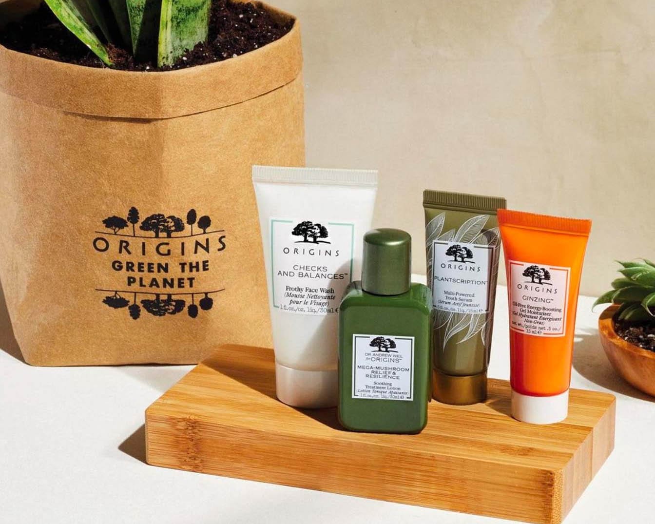 Zestaw kosmetyków Origins na drewnianej podstawce, w tym żel do mycia twarzy Checks and Balances, lotion Mega-Mushroom Relief & Resilience, serum Youth Serum Plantscription i nawilżający żel Ginzing.