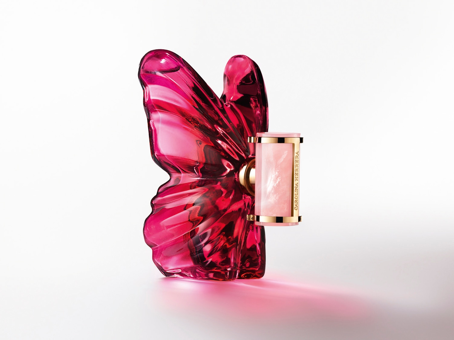 Funkelnder, pinkfarbener Glasflakon in Schmetterlingsform von Carolina Herrera, der Eleganz und Verspieltheit vereint.