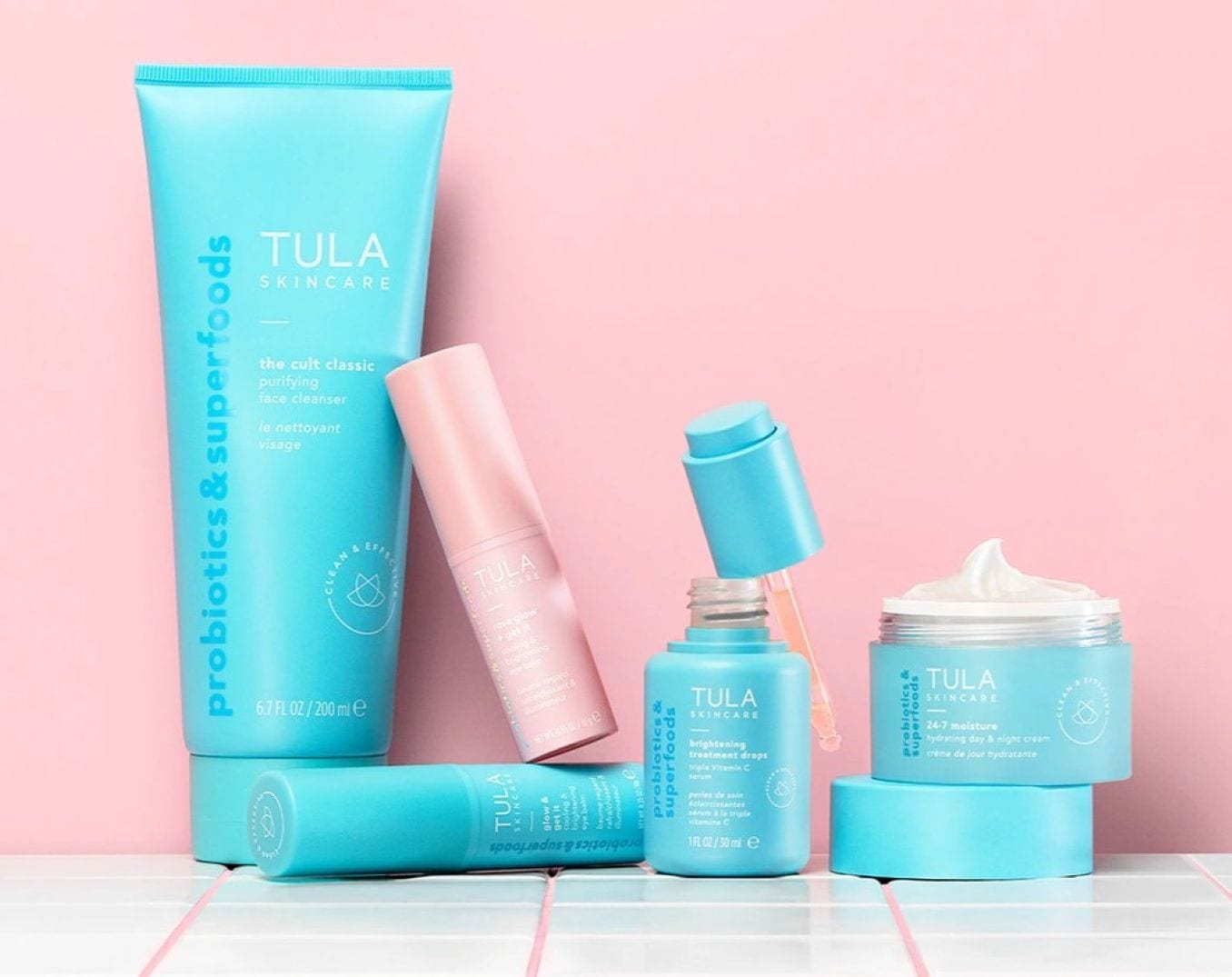 Eine Auswahl an Tula Hautpflegeprodukten in hellblauen und rosa Verpackungen, darunter Gesichtsreiniger, Seren und Feuchtigkeitscreme.