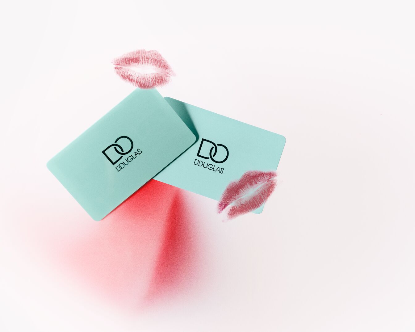 Dwie turkusowe karty podarunkowe Douglas z odciskiem ust na białym tle, idealne na prezent dla bliskiej osoby.