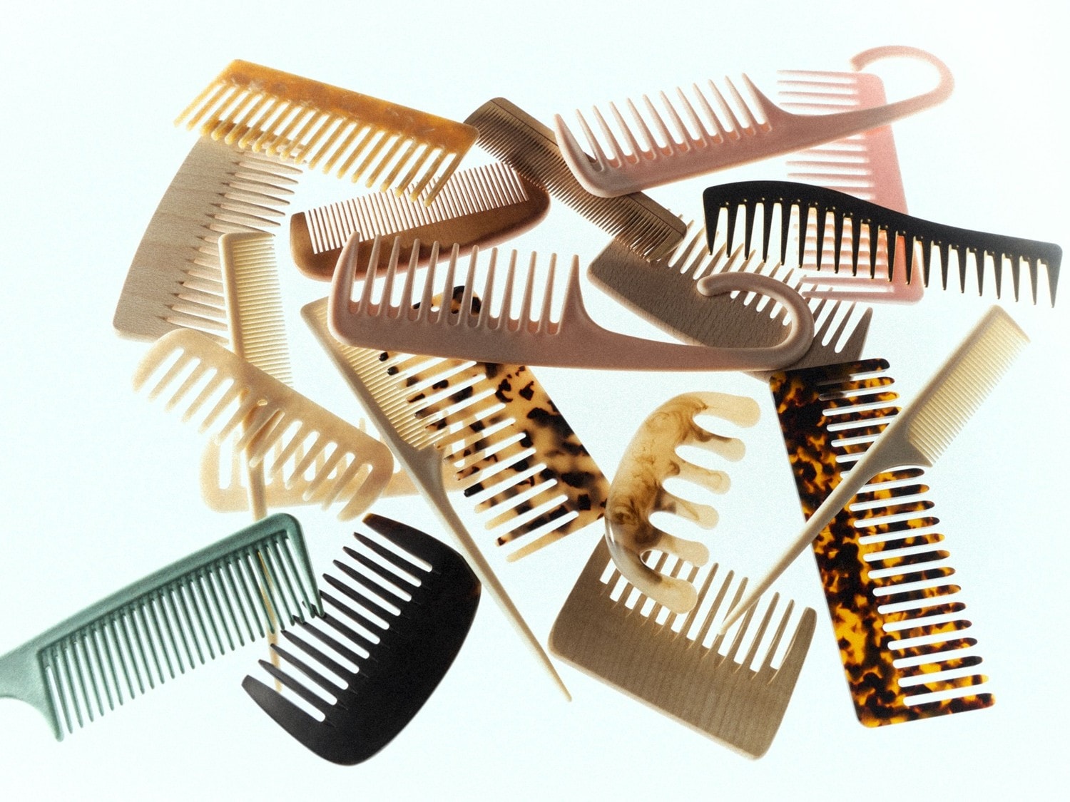 Een verzameling kammen in verschillende kleuren en stijlen, waaronder bruin, zwart, beige en gevlekt, liggen door elkaar.