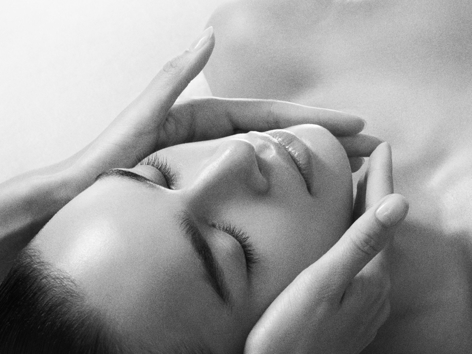 Nahaufnahme einer Frau, die eine entspannende Gesichtsmassage erhält, wobei die Hände sanft ihr Gesicht berühren.