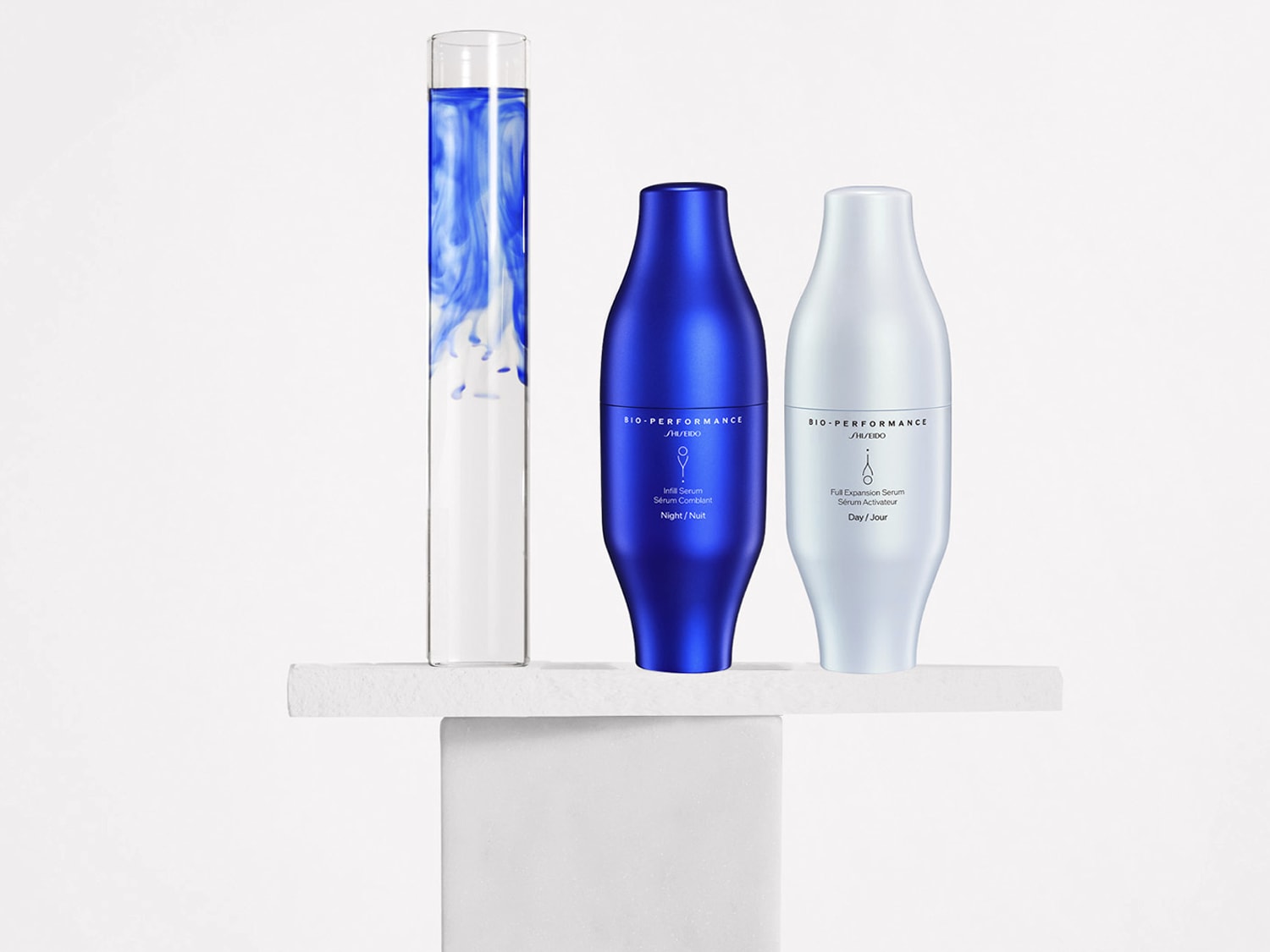 A Shiseido Bio-Performance Infill Serum éjszakai használatra, kék üvegben, mellette a nappali használatra szánt Full Expansion Serum világoskék üvegben, mindkettő egy fehér alapon áll.