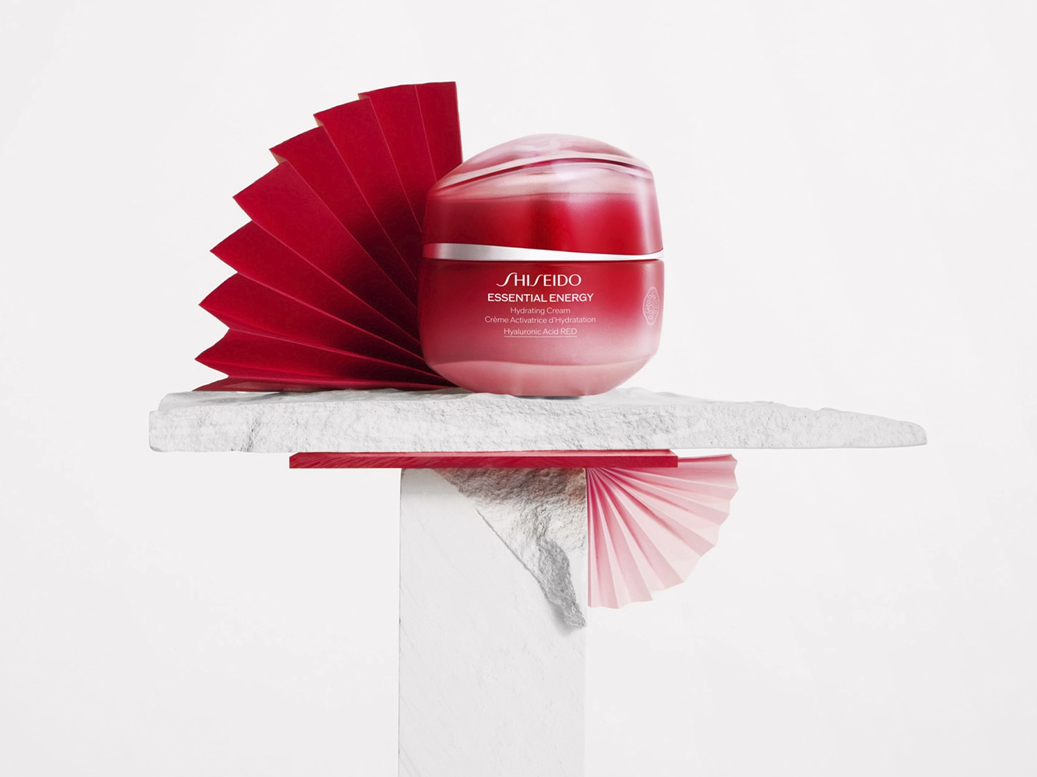 A Shiseido Essential Energy hidratáló krém piros tégelyben, fehér alapon, piros papírdíszekkel körülvéve.