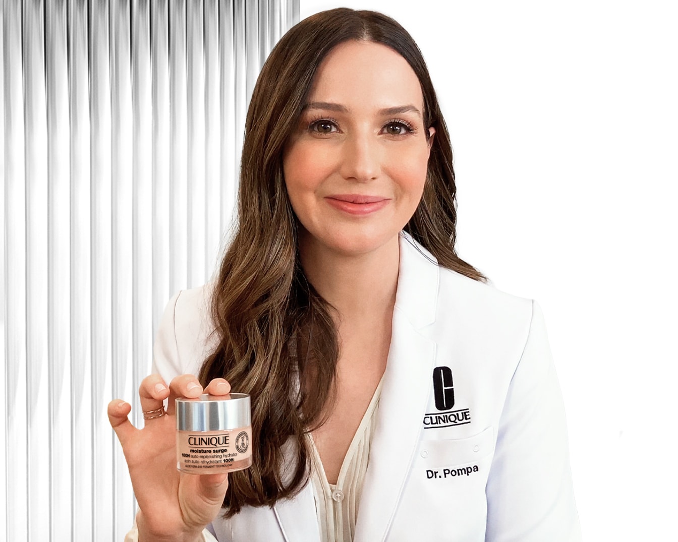 Dr. Pompa egy Clinique Moisture Surge hidratálót tart a kezében, mely 100 órás hidratálást biztosít aloe vera és fermentációs technológiával.