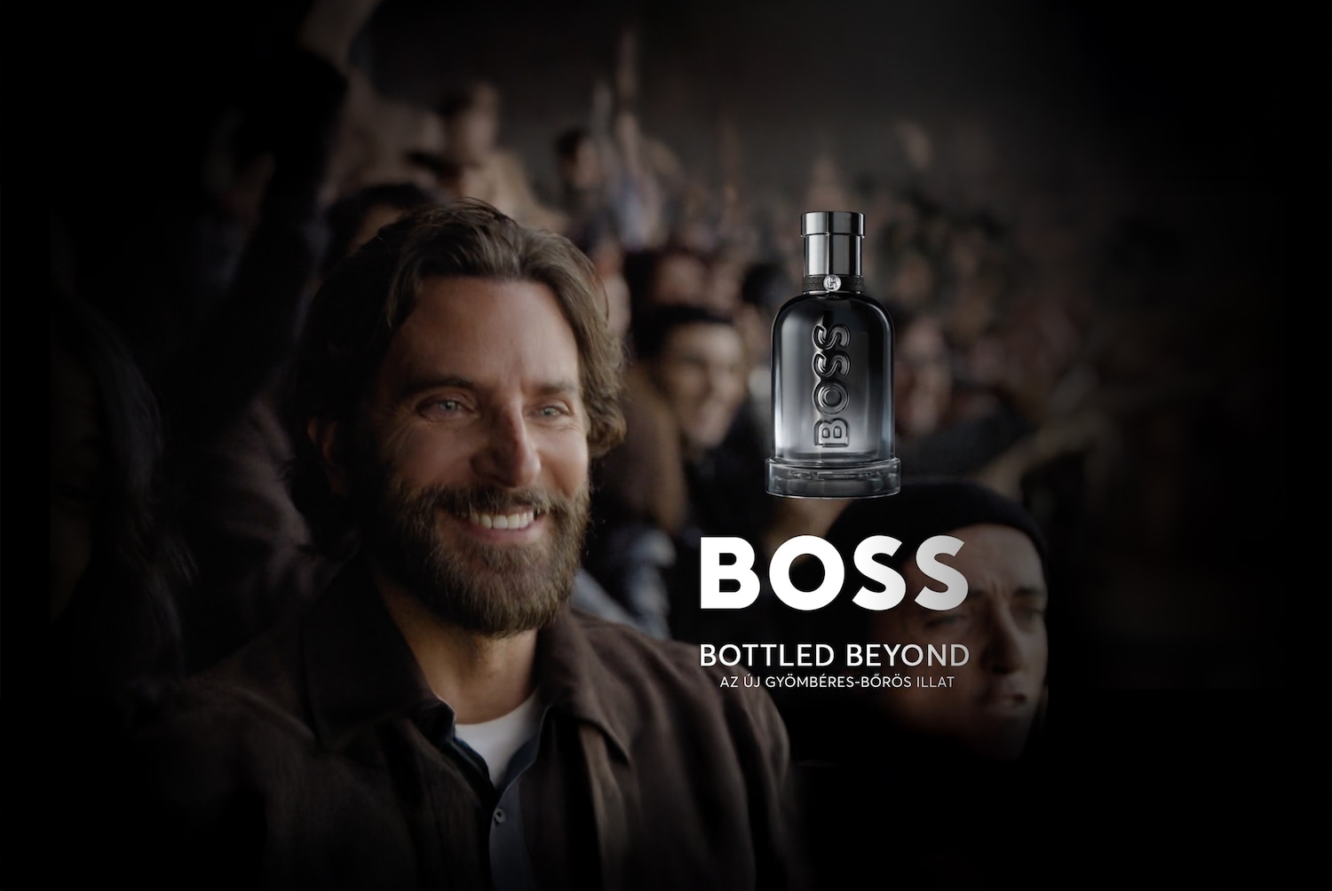 A BOSS Bottled Beyond parfümöt egy mosolygó férfi és egy tömeg előtt mutatják be, az "új gyömbéres-bőrös illat" felirattal.