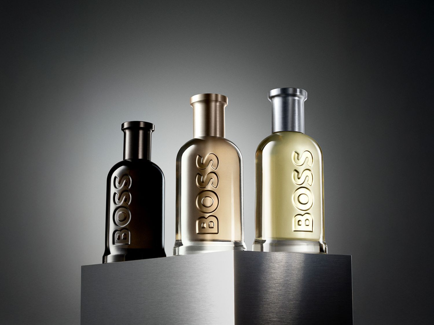 A BOSS The Scent parfüm üvege látható, melynek aranyszínű folyadéka elegáns, szögletes üvegben található, a márka neve dombornyomással.