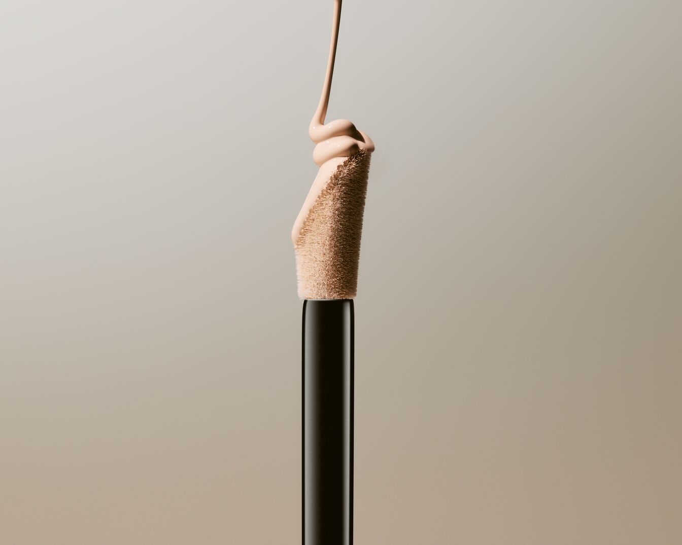 Šviesiai smėlio spalvos kreminis skystis teka nuo juodo aplikatoriaus šepetėlio, skirtas odos netobulumams paslėpti.