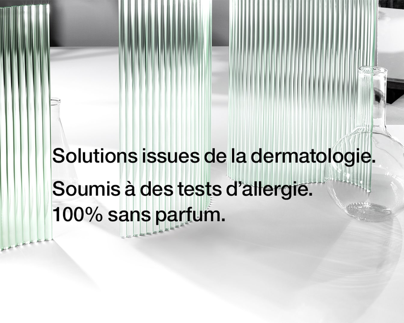 Des solutions issues de la dermatologie, soumises à des tests d'allergie et 100% sans parfum, présentées avec des verreries de laboratoire.