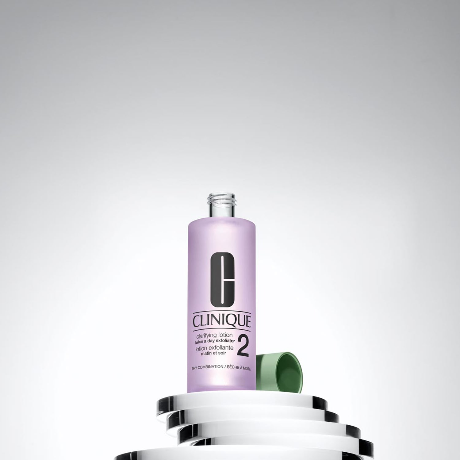 Die Clinique Clarifying Lotion in einer lila Flasche mit grünem Deckel steht auf einem Podest aus Glas.