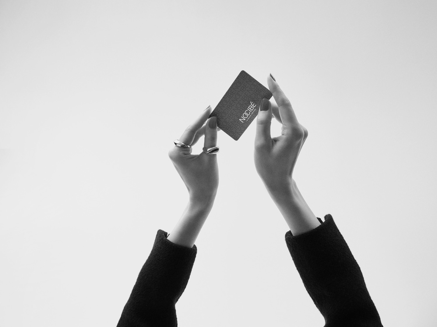 Deux mains gantées tenant une carte Nocibé, symbole d'élégance et de beauté à portée de main.