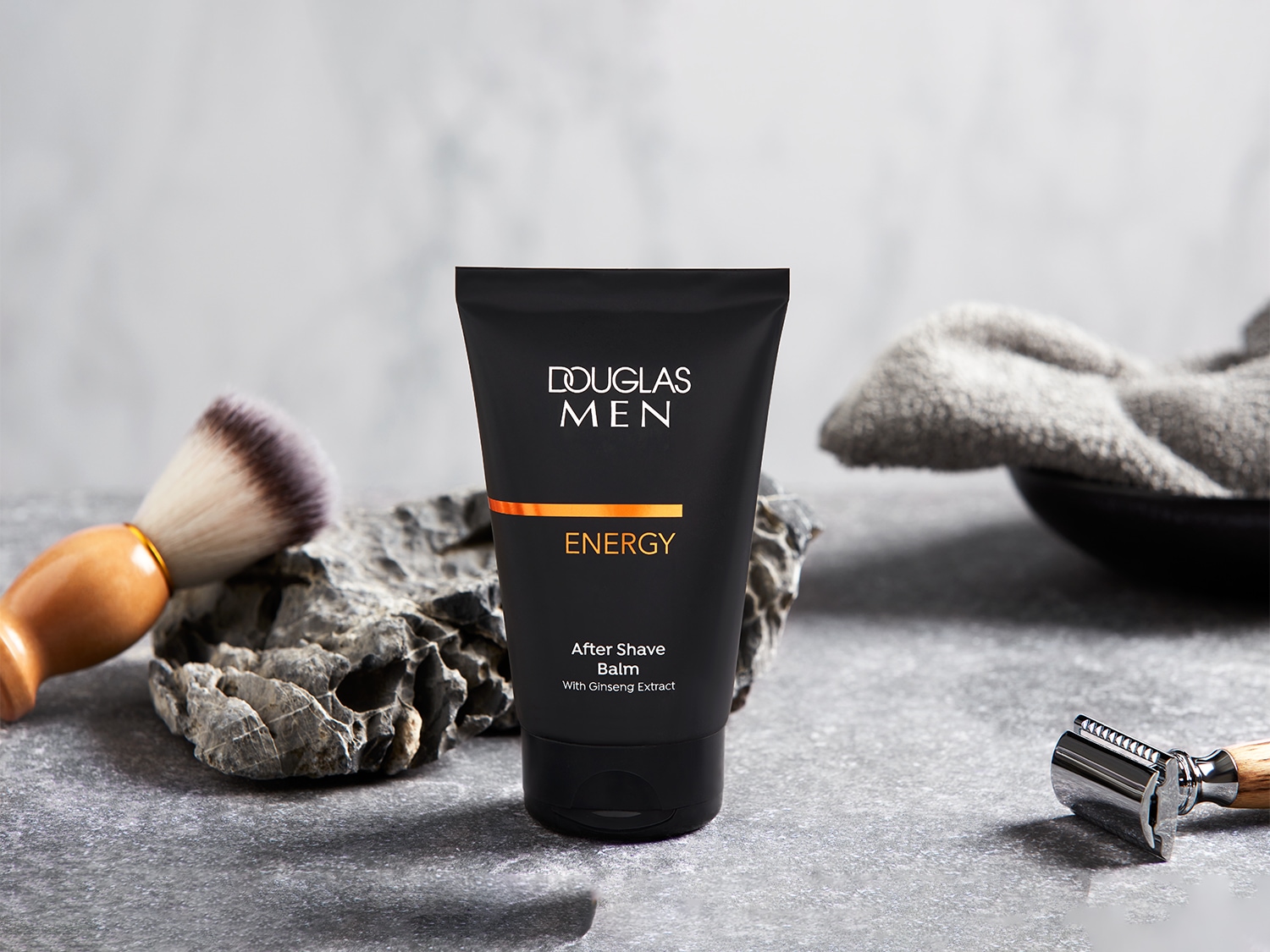 Tube noir de baume après-rasage Douglas Men Energy, enrichi en extrait de ginseng, pour une peau revitalisée après le rasage.